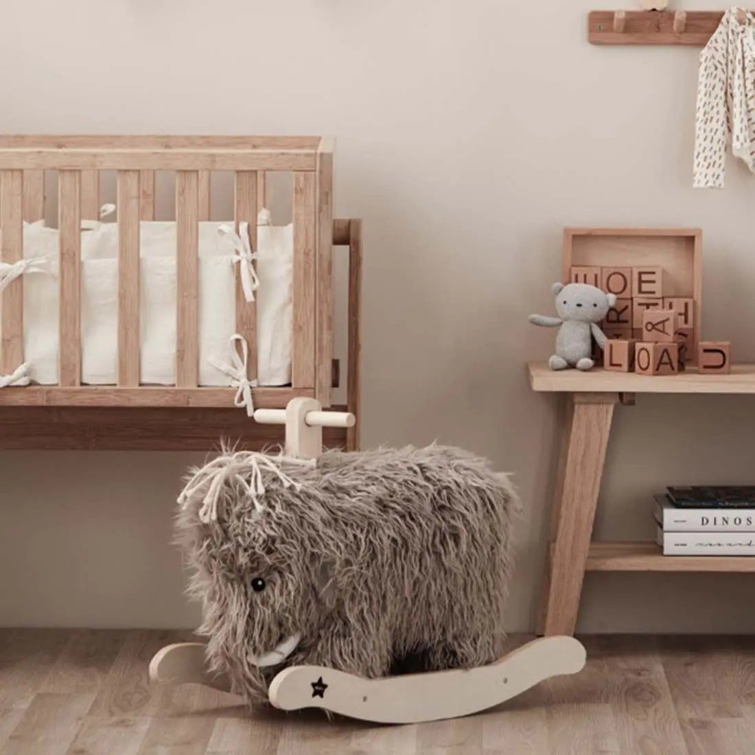 Rocking mammoth toy in a child's nursery next to a crib and some toys in the background.