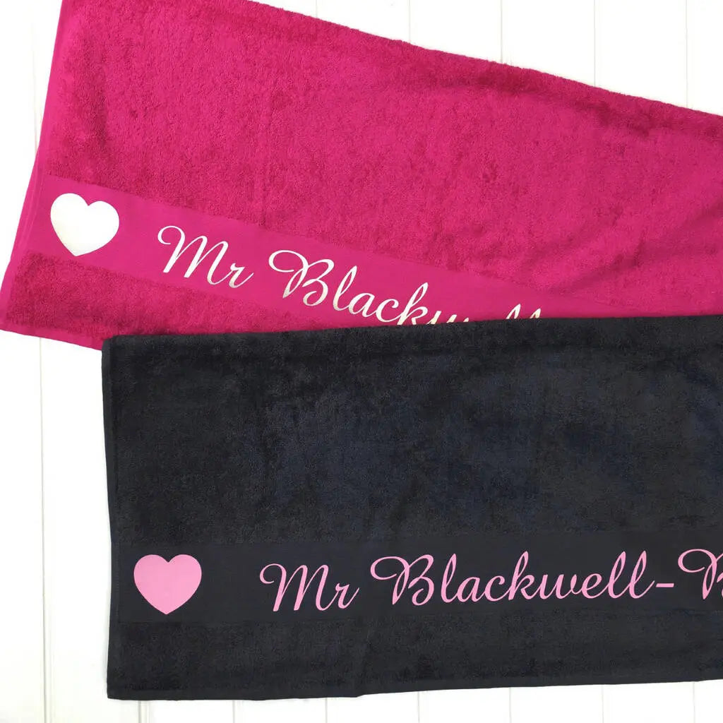 Two towels, one pink, one navy, both printed with the name Mr Blackwell with hearts either side the name