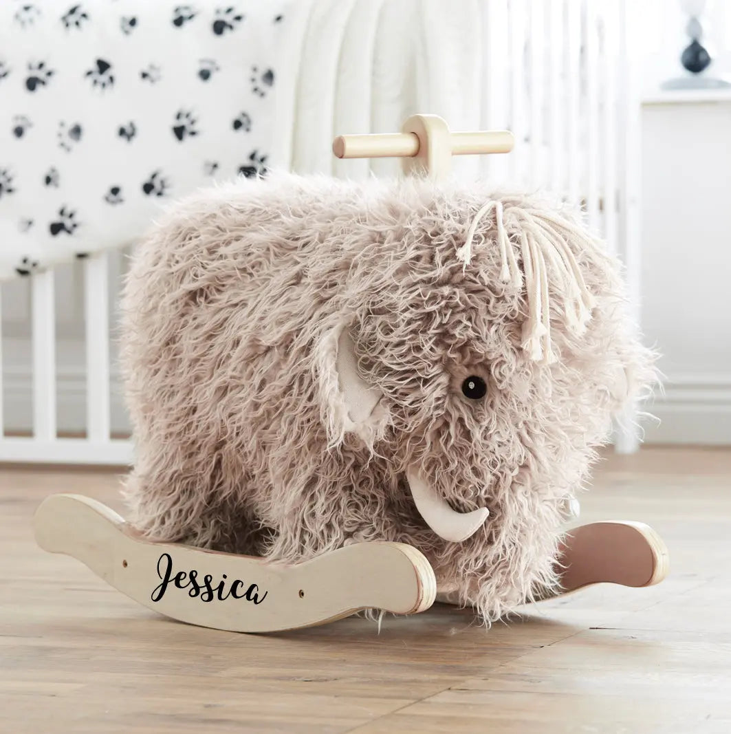 Personalised rocking mammoth toy with the name Jessica printed on the rockers. The mammoth has a trunk and horns, with a lot of shaggy fur. Situated in a child's bedroom