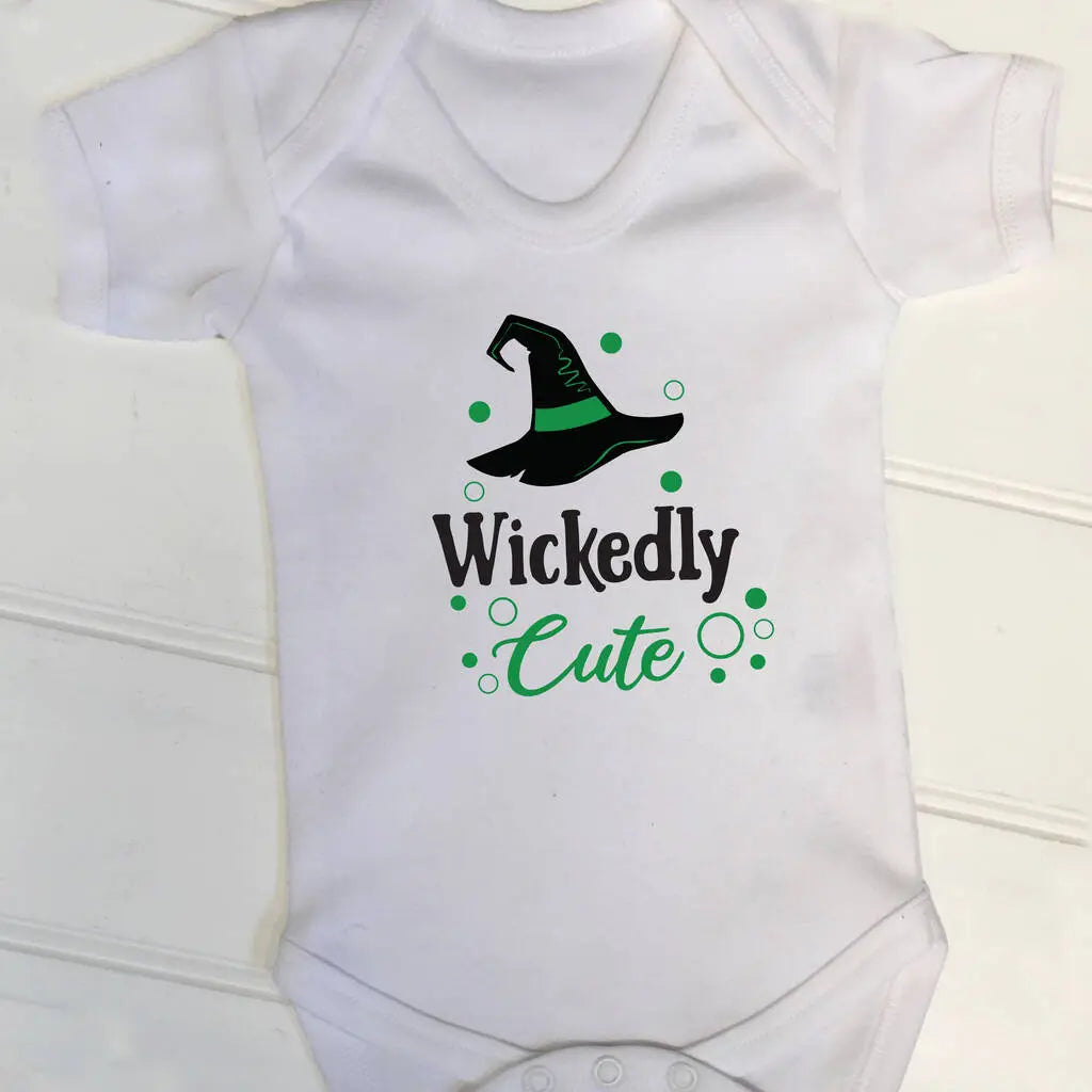 White babygrow with a cute halloween design. There is a witches hat and the text Wickedly Cute underneath, printed in black and green on the front.