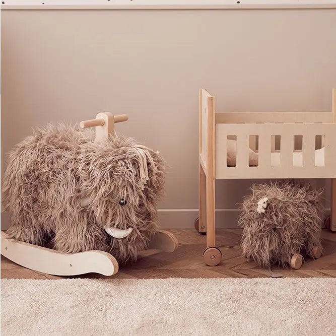 Rocking mammoth toy placed next to a toy crib. Underneath the crib is a pull along mammoth.
