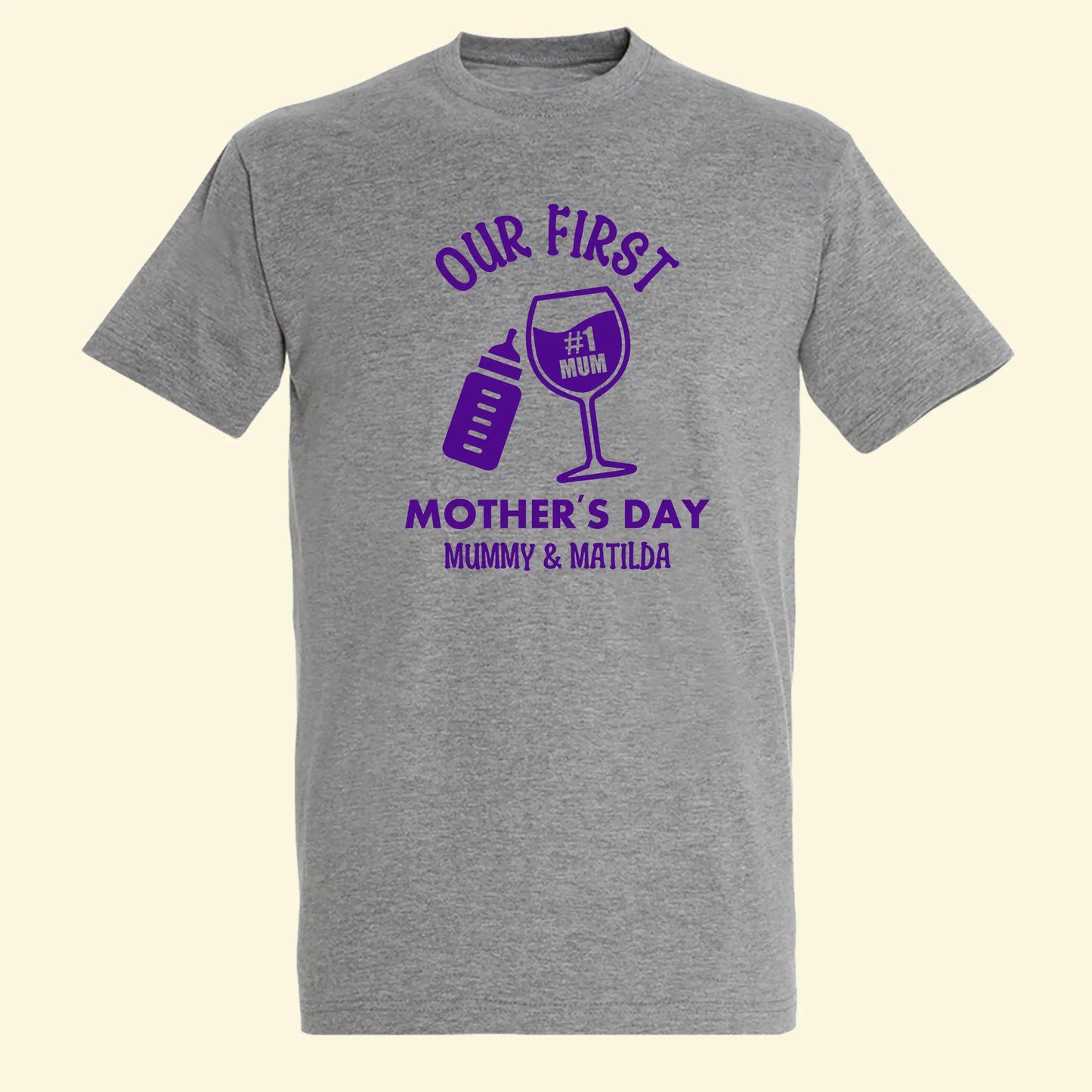 Grey adults t shirt with design of Our First Mother's Day Mummy & Matilda. With a baby bottle and wine glass tilted together. Printed in purple