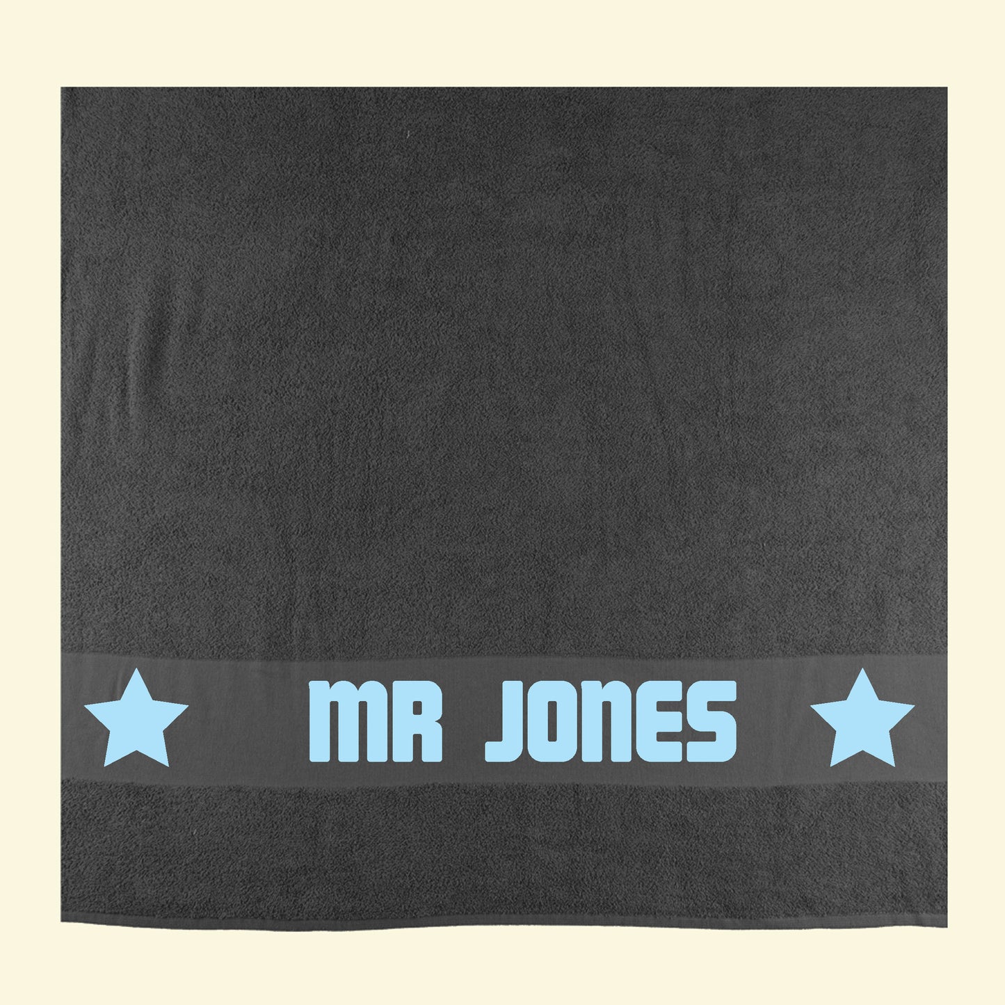 Dark grey towel with Mr Jones printed in the middle of two stars in light blue