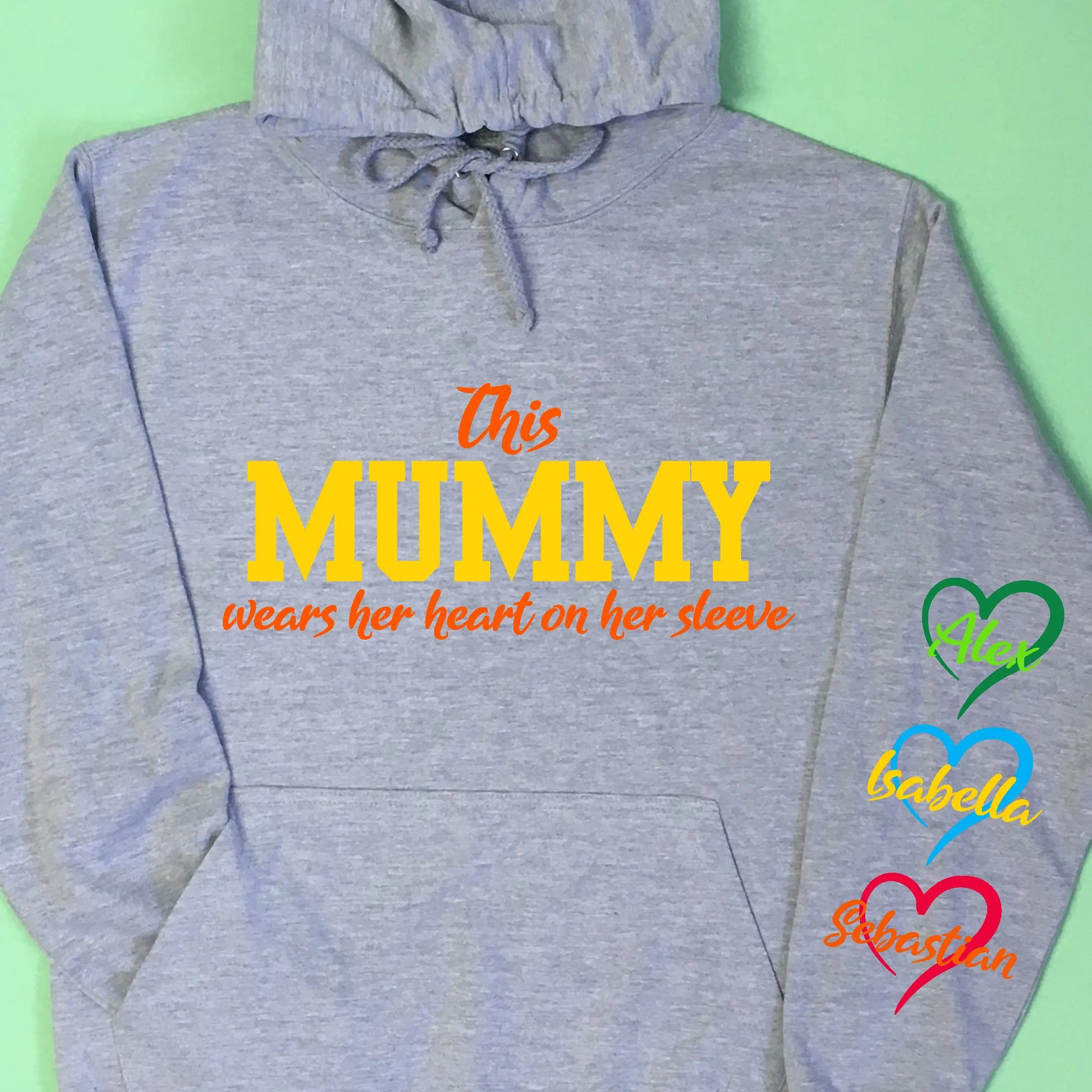 Adult grey hoodie, with This Mummy wears her heart on her sleeve printed on the front in two print colours. Down the right sleeve as photo (left hoodie when wearing) three hearts printed with child's names in the middle