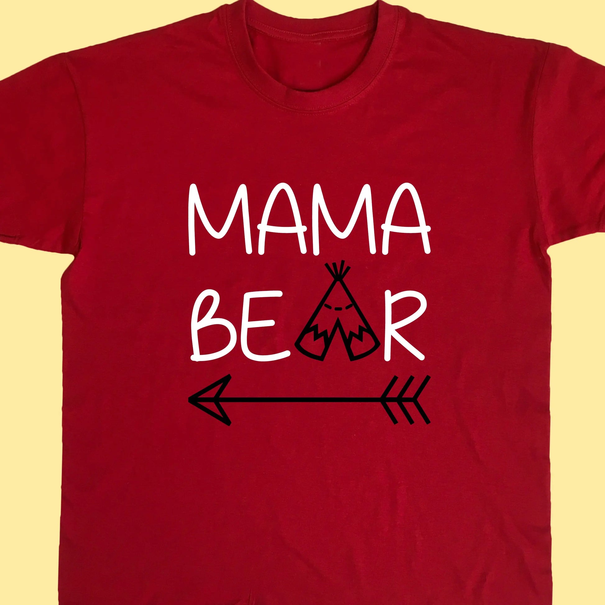 Red adult t shirt with top line of text reading Mama and the second reading bear but with the a replaced with a teepee and an arrow under the whole design. Printed in two colours text printed in white and teepee and arrow in black.