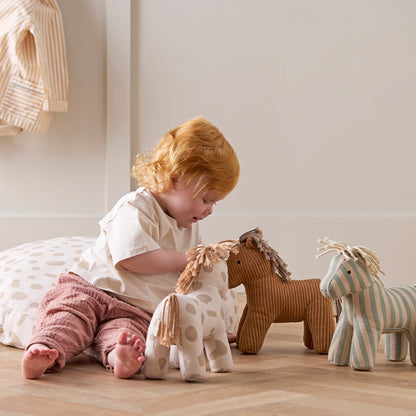 Little Girl playing with all three soft toy horses.