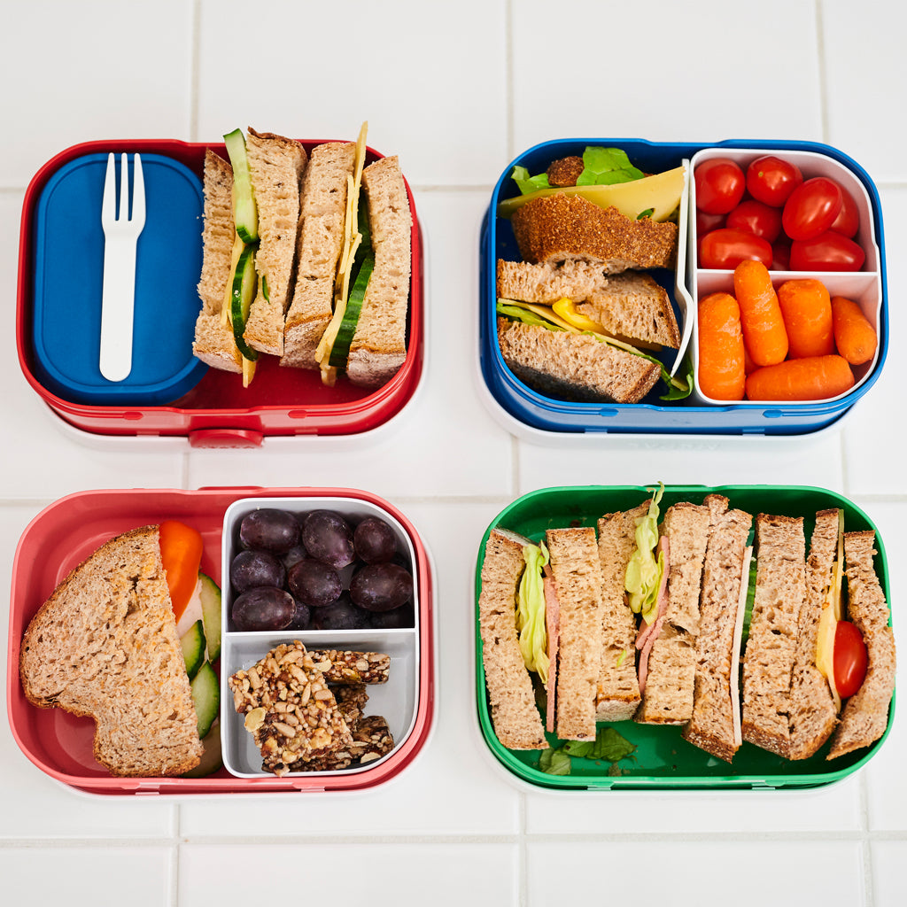 Four lunch boxes showing the inside of them and the different ways you can arrange your lunch. With fruit box / sandwiches, with the divider that comes with the lunch box or no divider just an open space.