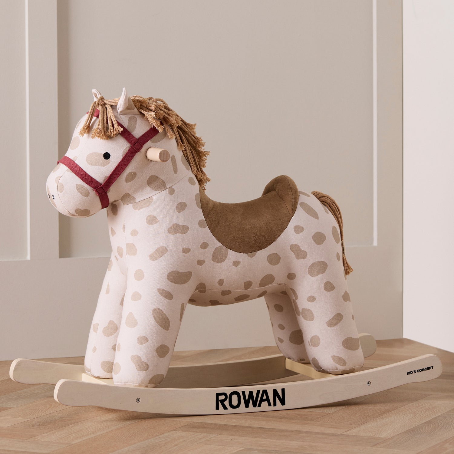 Rocking horse Dotty in a cream room with the name Rowan printed on the rockers