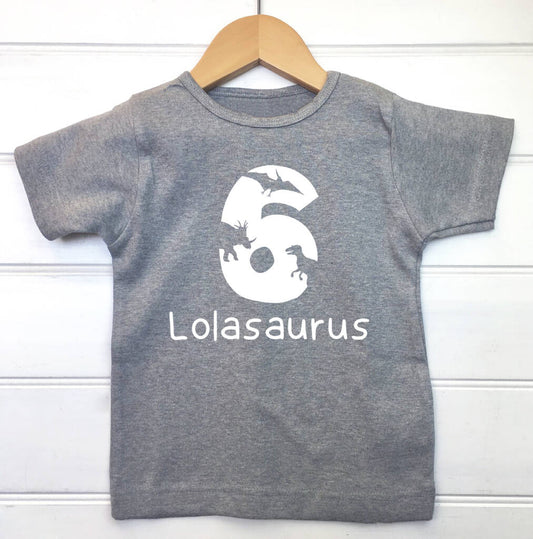 Children's grey personalised dinosaur birthday t shirt with the name Lolasaurus and the number six printed on the front in white. The number has images of various dinosaurs scattered through it.