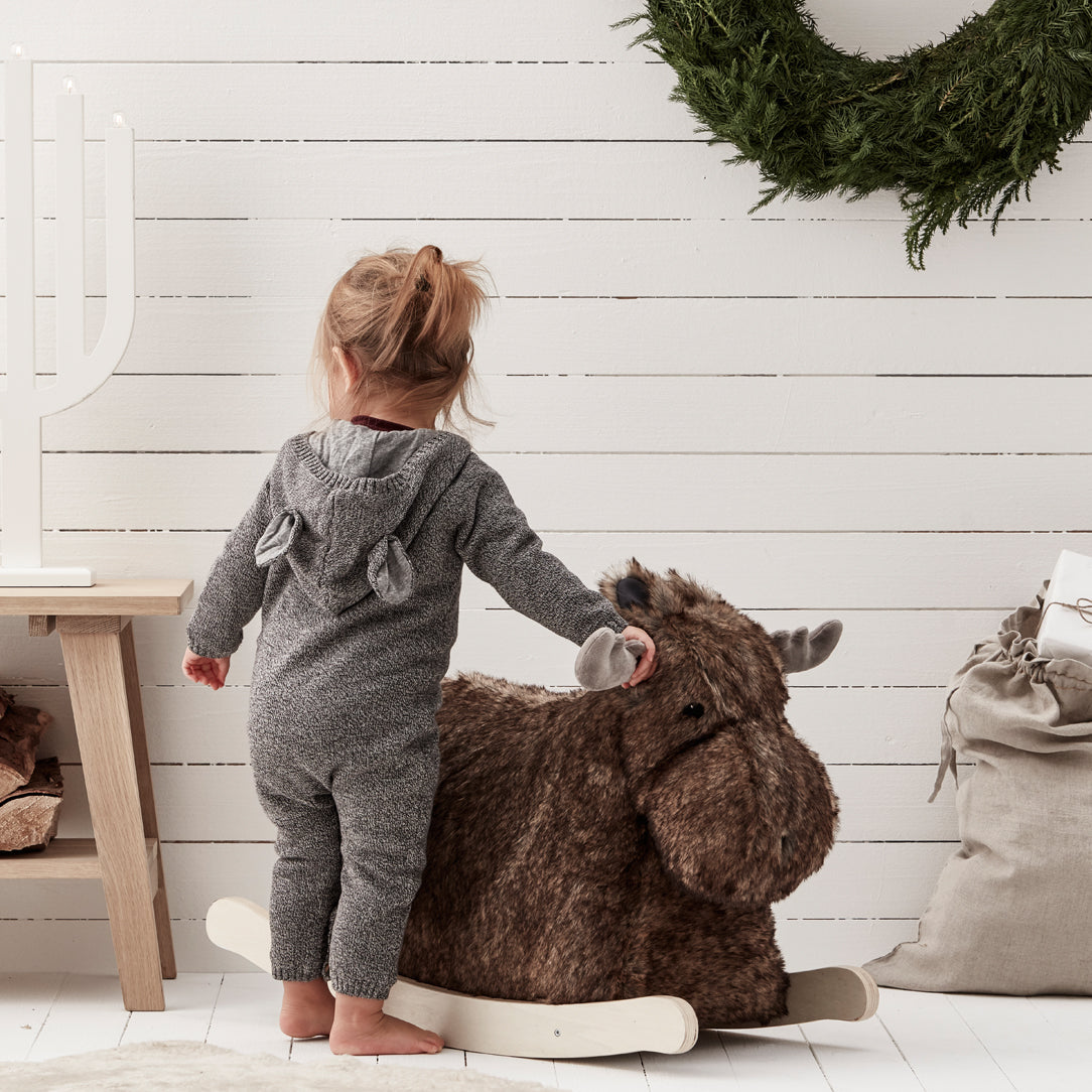 Small child playing with a rocking moose toy