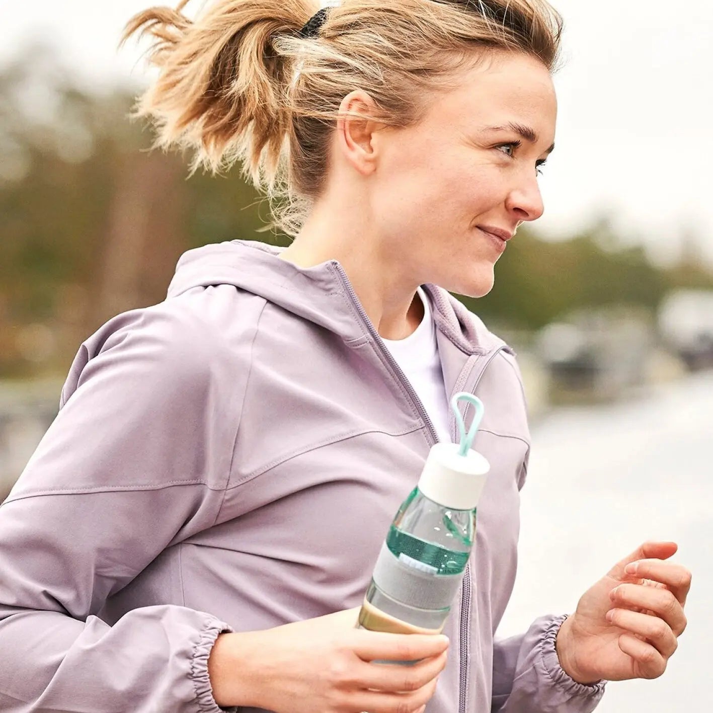Women running with a nordic green ellipse water bottle in her hand