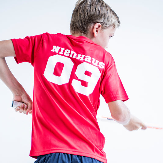 Red kids sport shirt with a name and number printed in sports world in white.