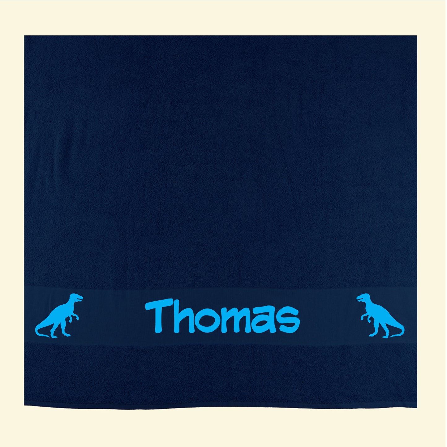 Navy beach towel with the name Thomas and t rex dinosaur images either side, printed in blue.