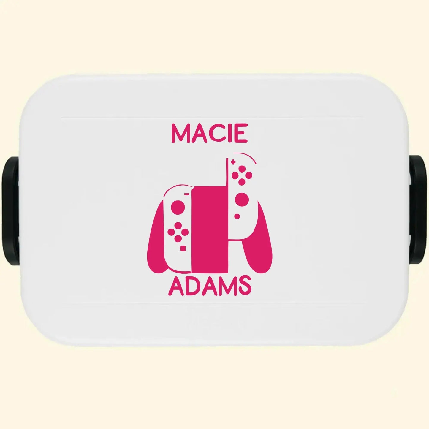 White lunch box with a game controller and the name Macie Adams printed in pink