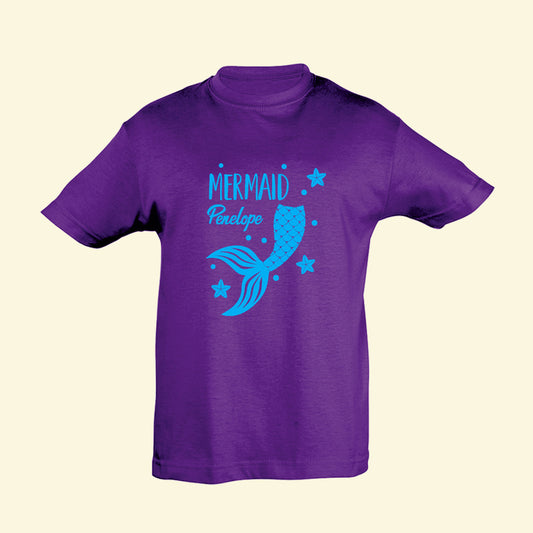 Purple t shirt with a blue mermaid tail and star fish printed on the front with the text Mermaid Penelope