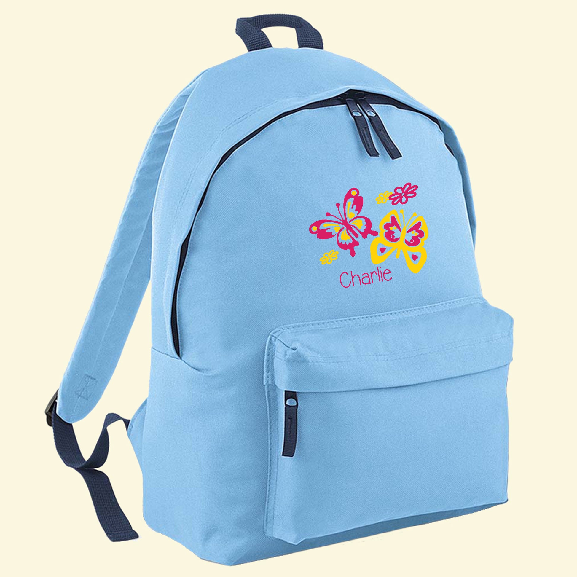 Light blue backpack with a front pocket. On the front there is a butterfly design in pink and yellow colours and the name Charlie