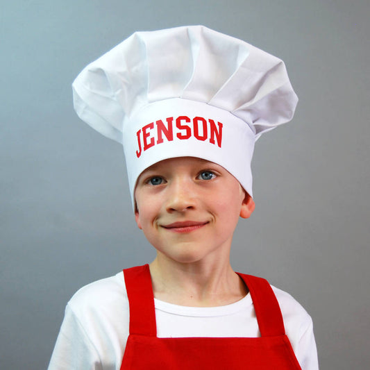 Boy wearing a white chef hat with the name Jenson printed in red on the front.