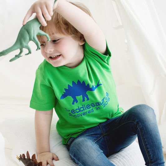 Boy wearing a dinosaur t shirt in Green with a Stegosaurus and dinosaur name and when discovered