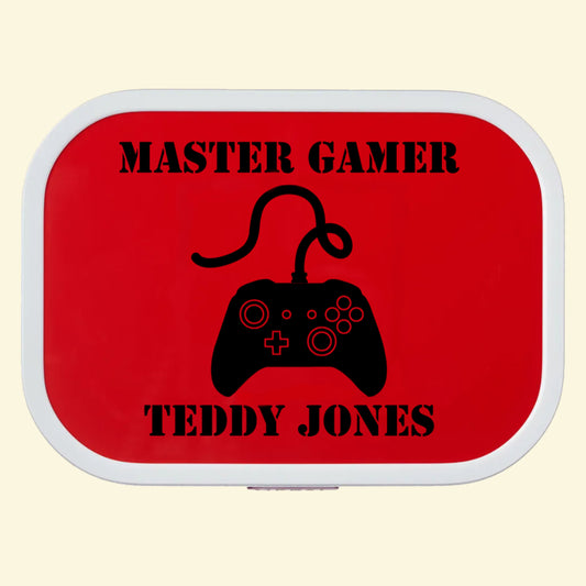 Red campus lunch box with a game controller printed in the middle, with the text Master Gamer above and Teddy Jones below in an army style font on the lunchbox lid