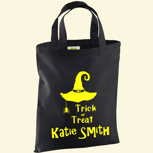 Black small cotton bag with a witches hat, spider and Trick or Treat. The child's name is printed underneath in a vibrant yellow