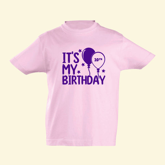 Light pink t shirt with It's My Birthday printed on the front in purple with stars and balloons. In side one of the balloons is  10th for how old they are.