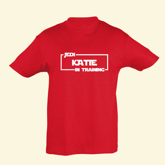 Red t shirt with a Star Wars style film surround, with the text Jedi In Training and the name Katie in the centre. Printed on the front