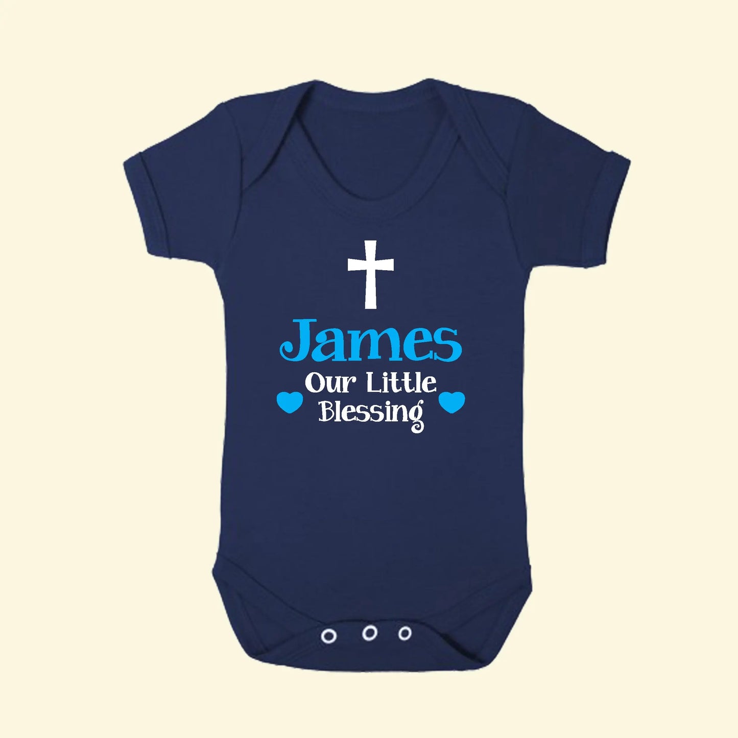 Navy blue Babygrow with a cross and James ur Little Blessing with hearts in white and blue print on the front