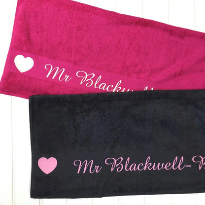 Two towels, one pink, one navy, both printed with the name Mr Blackwell with hearts either side the name