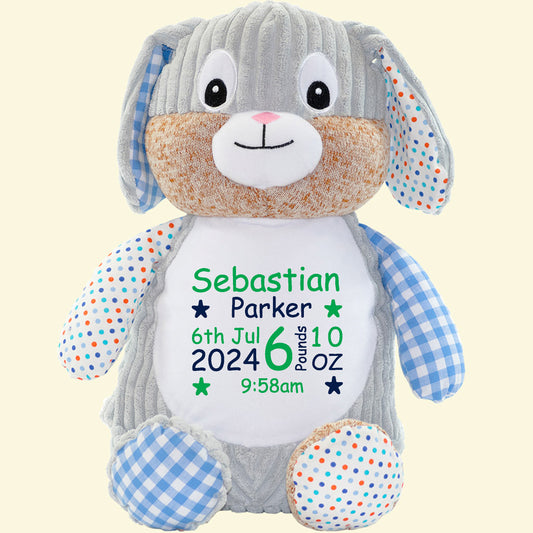 Cubbies harlequin blue bunny, with a mix of dotty and check fabric on the arms, ears and feet. The main bunny is made up of a textured grey fabric with a white plush belly. Embroidered on the belly is the baby's name, date of birth, time and weight at birth. A lovely keepsake