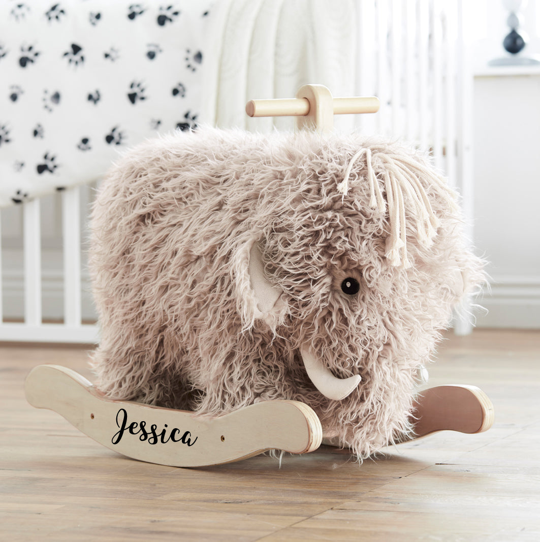 Personalised rocking mammoth toy with the name Jessica printed on the rockers. The mammoth has a trunk and horns, with a lot of shaggy fur. Situated in a child's bedroom