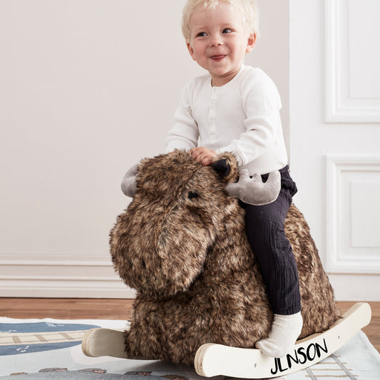 Personalised rocking moose toy with a cute little boy sitting on the rocker. The child's name is printed on the rockers. The moose has lovely grey antlers