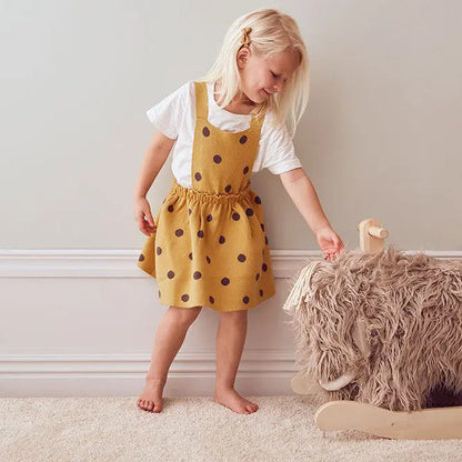 Girl standing next to a rocking mammoth toy, she is smiling and stroking the mammoth's head. It's a cream room, with a plush cream carpet.