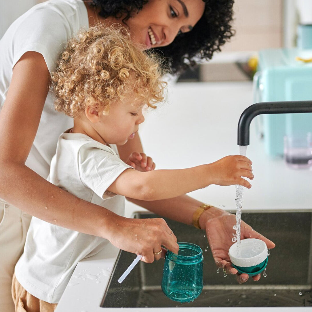 Mother and child washing the straw cup at the sink