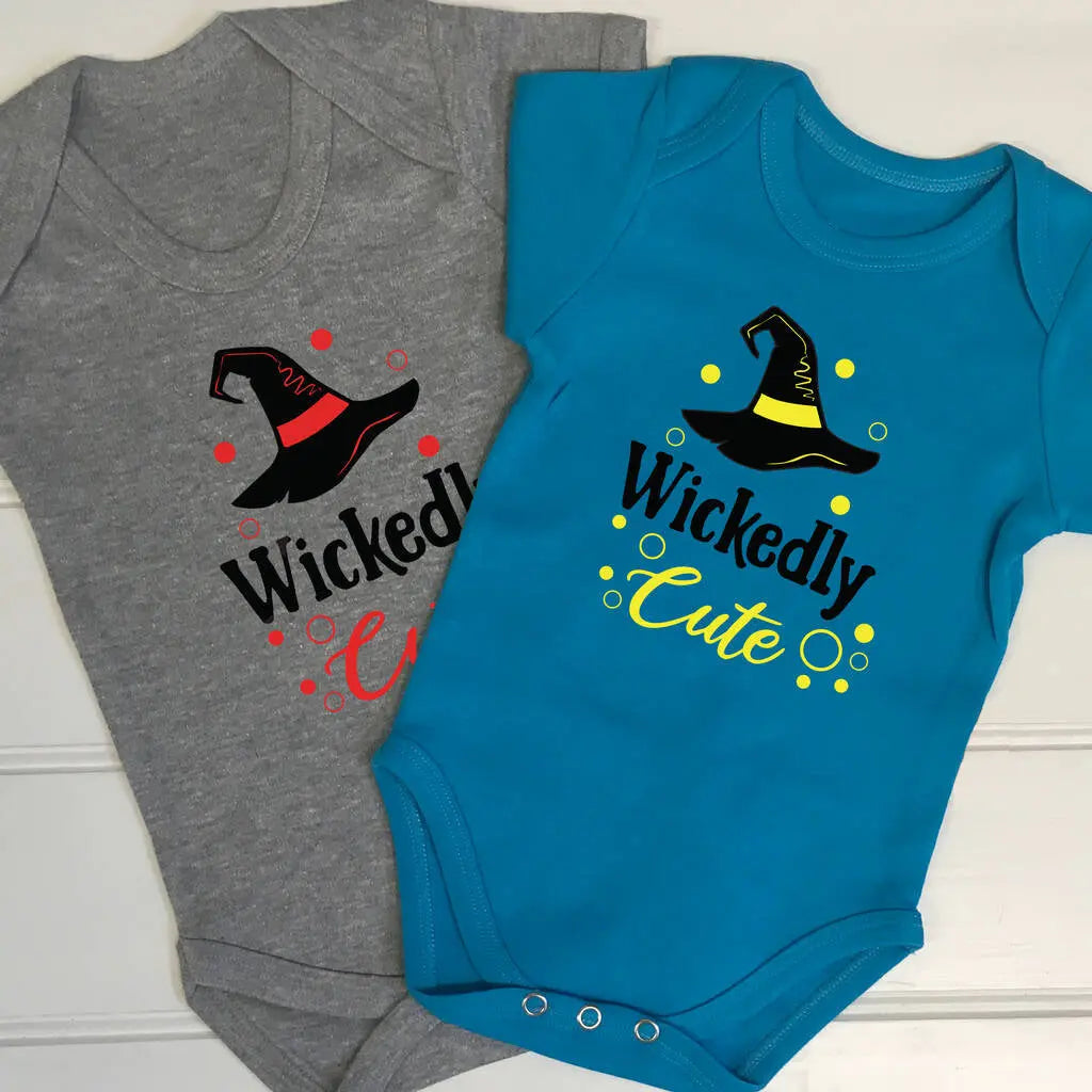 Two babygrows, one aqua blue and one grey. Both with a witches hat and Wickedly Cute printed on the front. The aqua blue has a black and yellow design and the grey babygrow has a black and red design. Great for Halloween or any other time of the year.